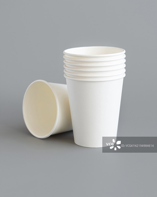 灰色背景上的白色纸质一次性杯子特写，环保，无塑料餐具图片素材
