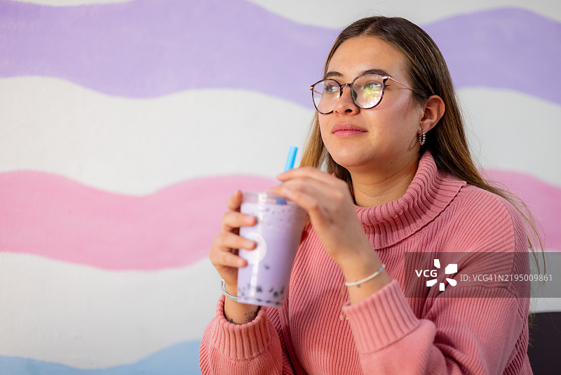 快乐的年轻女性在咖啡馆里享用她的冰沙图片素材