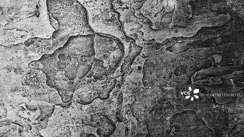 一面有锈蚀和裂纹的灰色石墙。粗糙的纹理。阳光与阴影。黑白色调。英国伦敦。图片素材