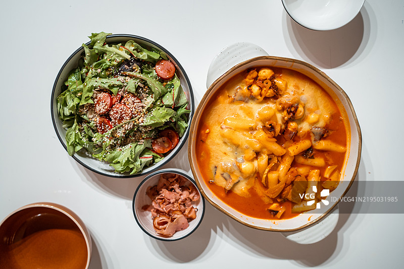 自制融合美食：韩式年糕配辣椒酱和火箭沙拉配切片香肠图片素材