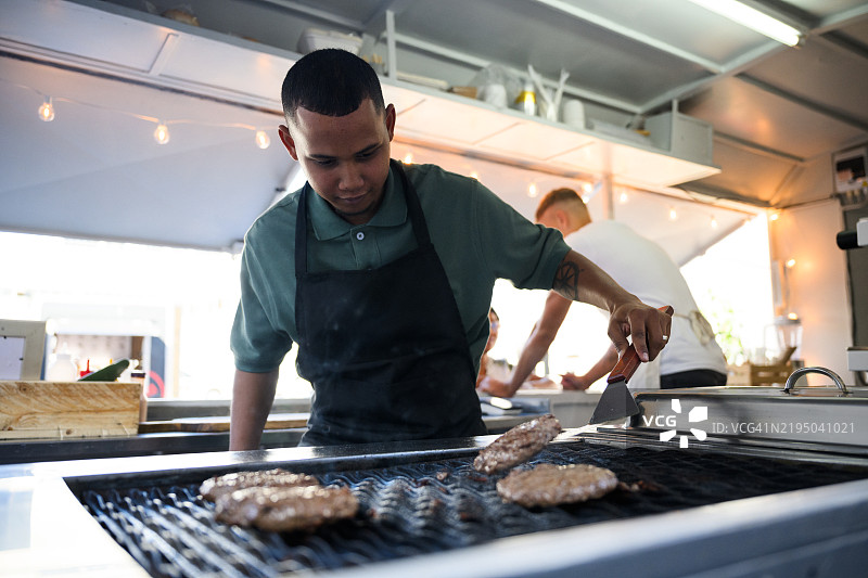 多种族男性厨师在城市餐车为午餐翻转汉堡图片素材