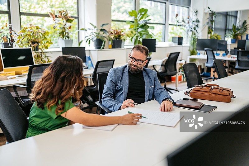 两位中年同事在澳大利亚悉尼的办公室桌前交谈图片素材