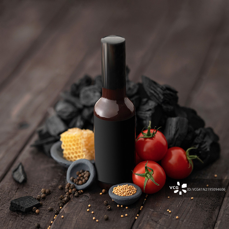 瓶装的番茄酱，加入蜂蜜和芥末，黑色炭火放在木桌上。烟熏甜酱的配料。烧烤酱，番茄酱，酸辣酱。调味料。腌料。食品概念。留白空间。图片素材