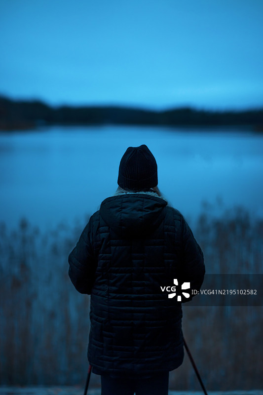 戴着帽子的女性独自站在海边的沙滩上图片素材