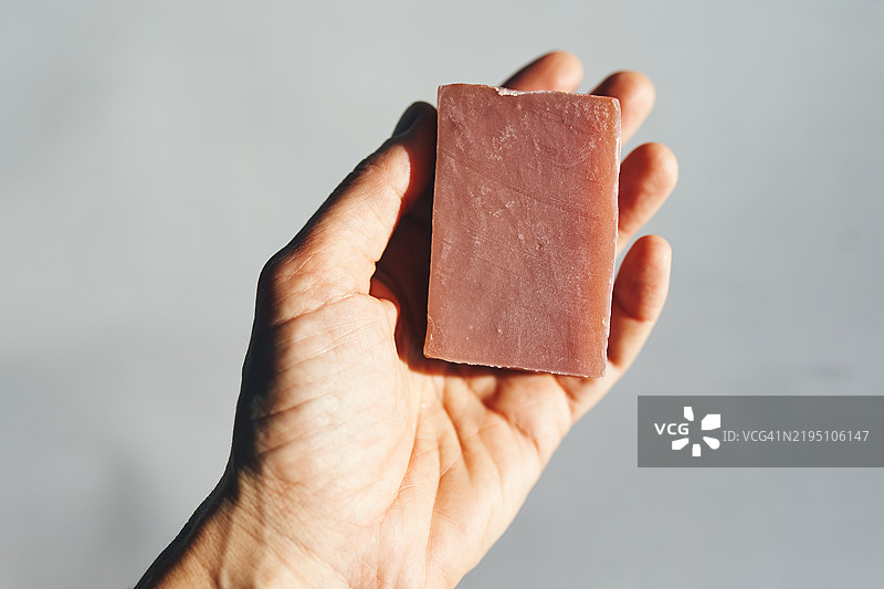 特写手握着一块古朴的紫色香皂图片素材