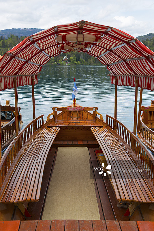 一艘木船的内部视图，红白相间的船顶漂浮在宁静的湖面上，布莱德湖，维尔德斯湖，上卡尔尼奥拉地区，戈伦斯卡，斯洛文尼亚，巴尔干，欧洲图片素材