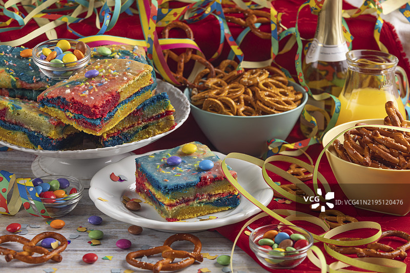 五彩缤纷的蛋糕和椒盐卷饼，旁边是饮料和派对装饰，嘉年华气氛图片素材
