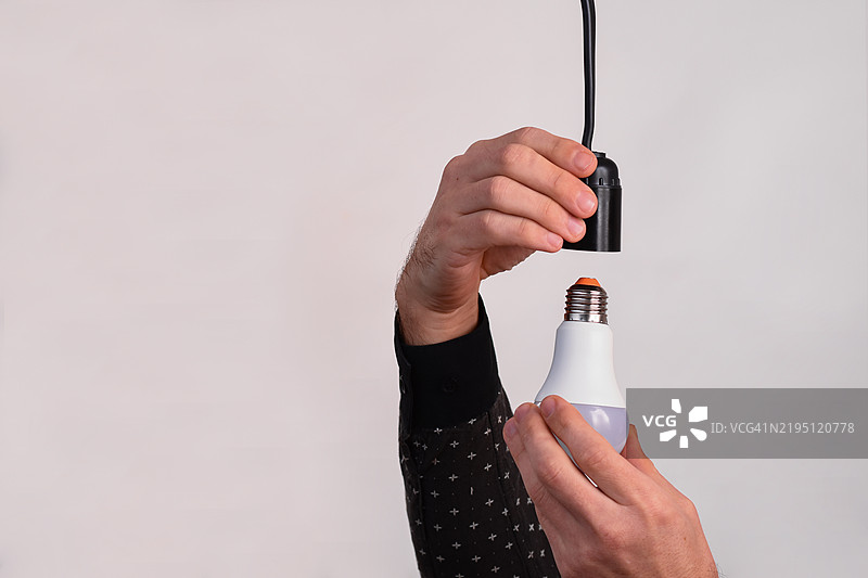 一名男子手中拿着LED灯，背景为白色。图片素材
