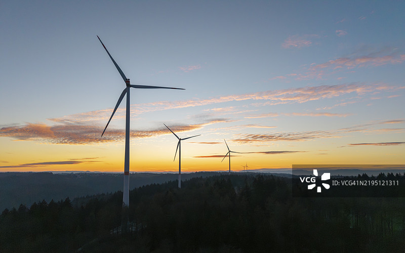 风力涡轮机在山丘上被五彩斑斓的日出逆光照亮，风电场，雷姆斯谷，巴登-符腾堡州，德国，欧洲图片素材