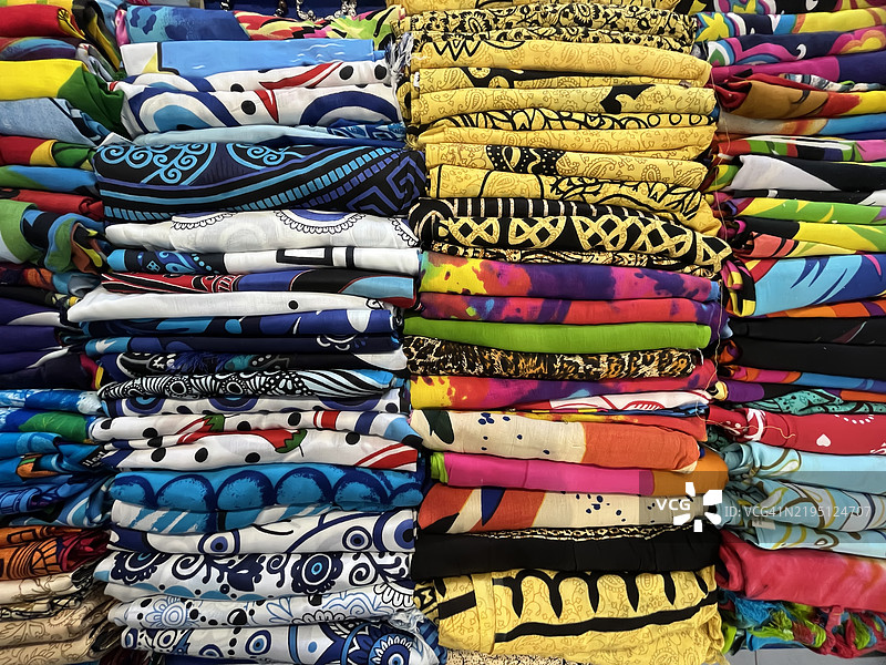 许多五颜六色的T恤叠放在桌子上。图片素材