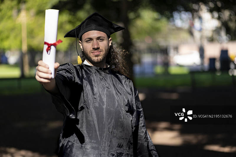 年轻男子穿着毕业服，男性获得学位，学术生涯图片素材