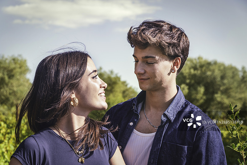 年轻的情侣在葡萄园游览时互相凝视，眼中充满爱意。图片素材