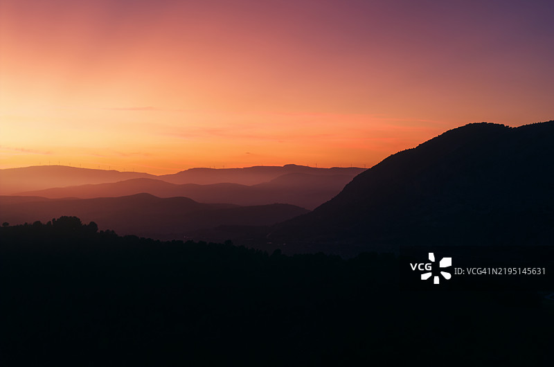 壮观的日落映照在山地平原上，俯瞰日落时分的迷人景色。图片素材