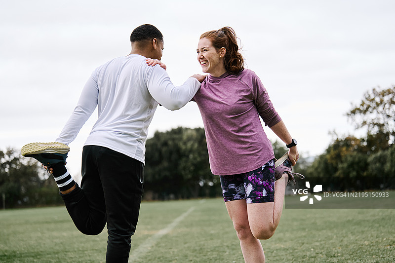 男女在运动场上进行腿部拉伸图片素材