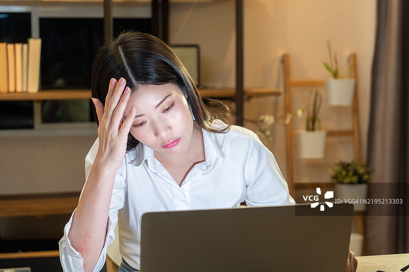 在家办公室里，感到沮丧的女性正在使用笔记本电脑。图片素材