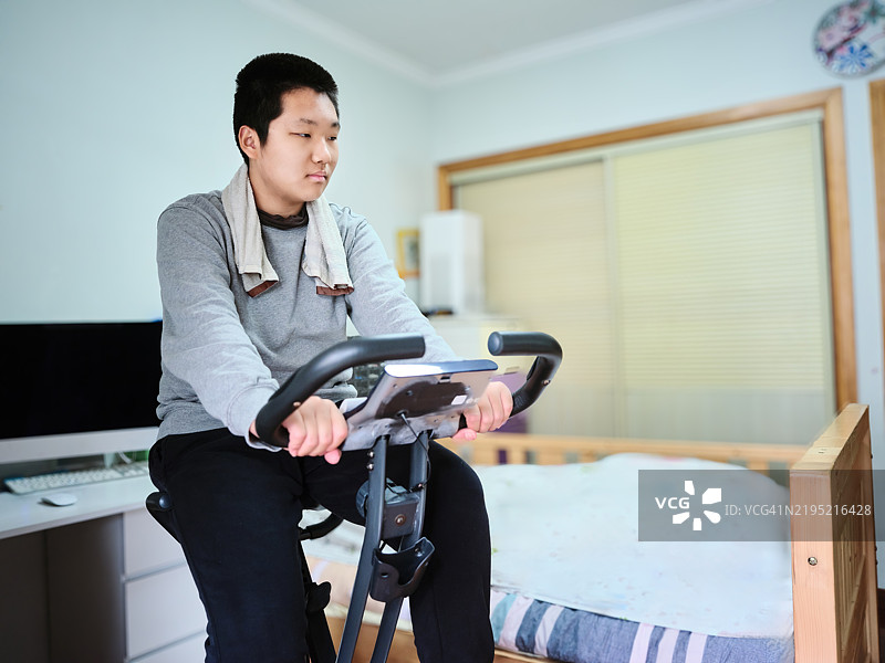 少年在家中骑动感单车锻炼图片素材