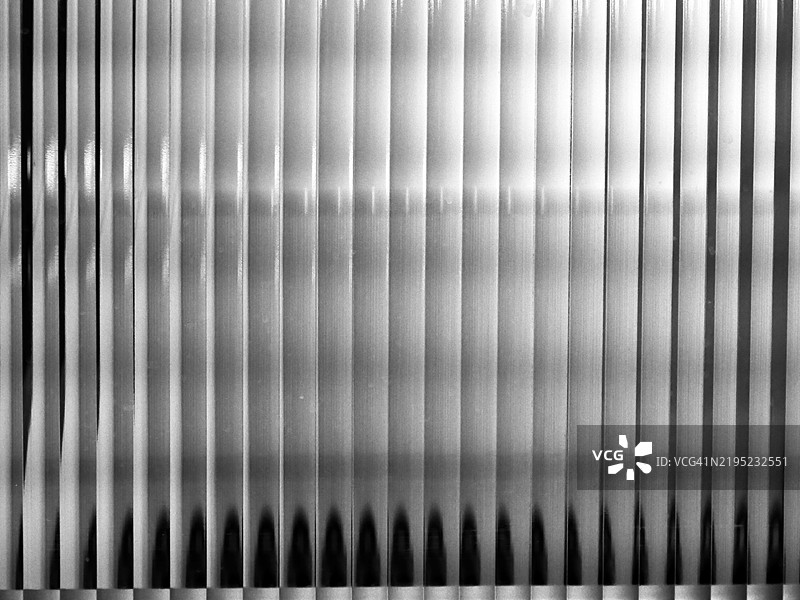 蒙特利尔，魁北克，加拿大的一个不透明且有条纹的玻璃窗透出的扭曲光线。阳光。黑白。图片素材