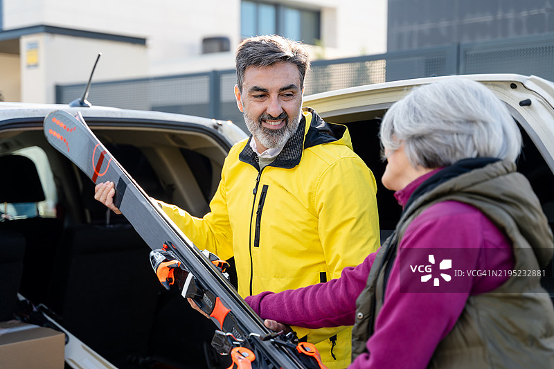 老年夫妇在滑雪旅行前将滑雪板装入汽车后备箱图片素材