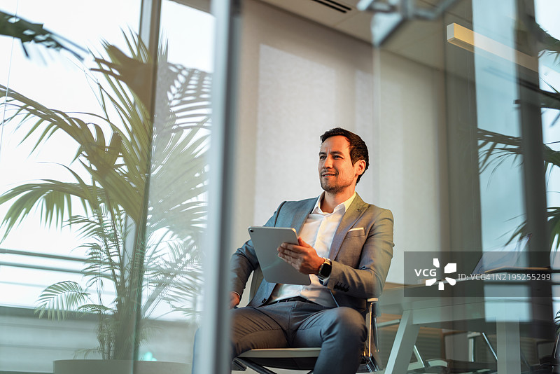 自信的商人在现代办公室环境中使用平板电脑图片素材