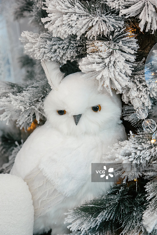 手工制作的白色毛茸茸猫头鹰，用于装饰圣诞树，背景是节日的雪景图片素材