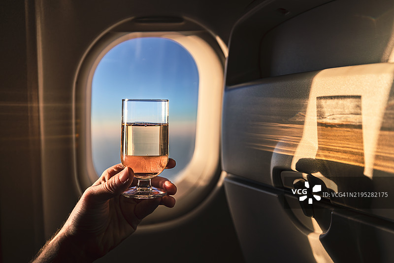 手握香槟杯靠在飞机窗户上图片素材