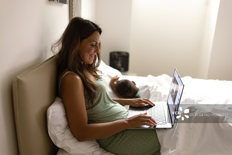 工作妈妈在床上，孩子在睡觉图片素材