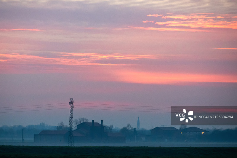 威尼斯平原的日落，远处有一群房屋图片素材