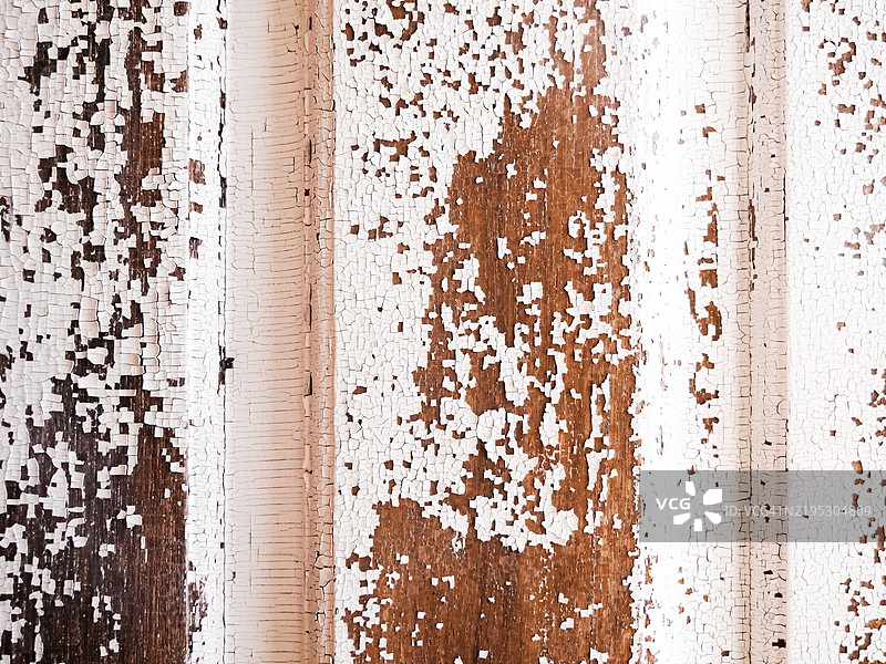 剥落白漆的风化木板特写，露出下面的棕色木材图片素材