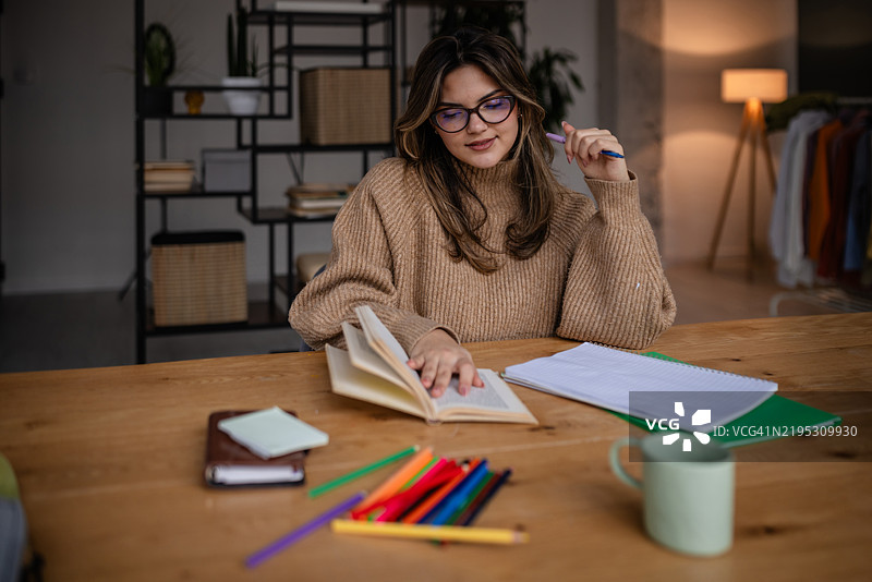 白天，女性在舒适的工作空间中用书籍和彩色笔学习图片素材