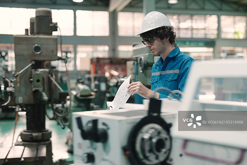 戴着安全帽的工程师在大型制造厂审查技术图纸图片素材
