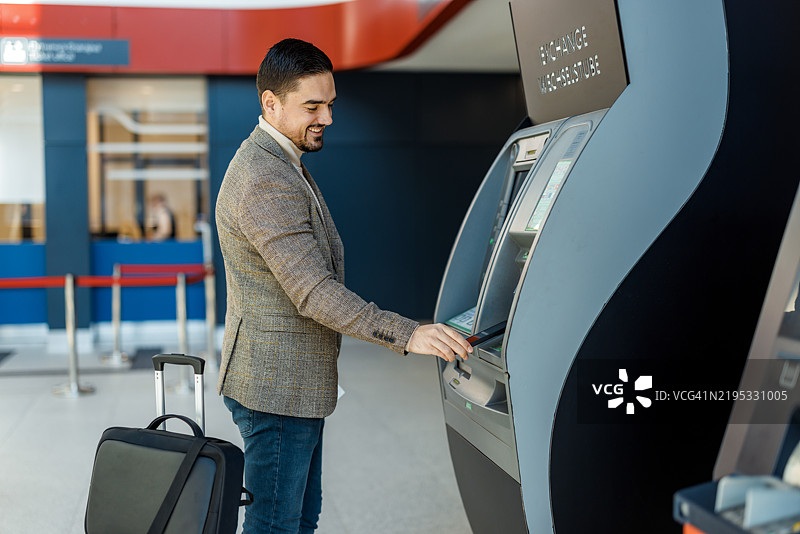 商人在机场航站楼的自动取款机上取款图片素材