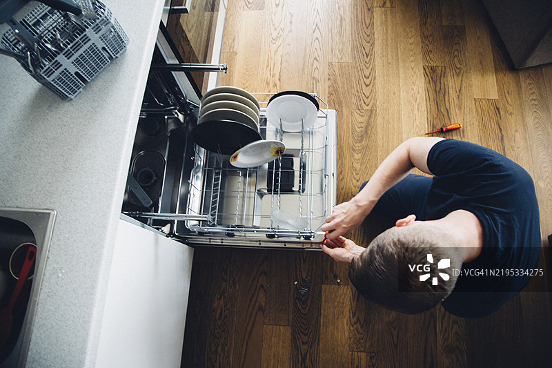 从高处俯视修理洗碗机的男人图片素材