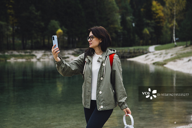女人在湖边站着用手机拍照图片素材