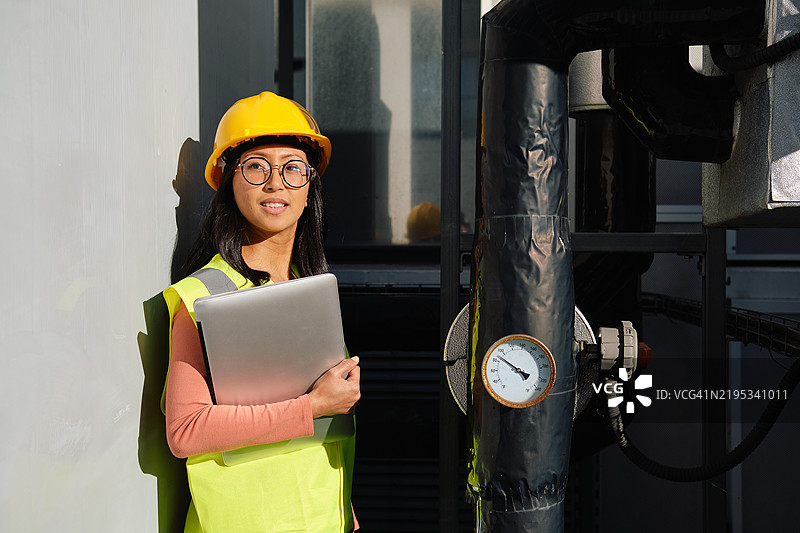 年轻女性工程师手持笔记本电脑检查工业管道图片素材