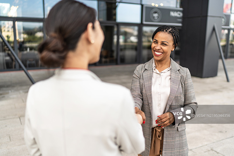 商务人士在办公大楼前握手图片素材