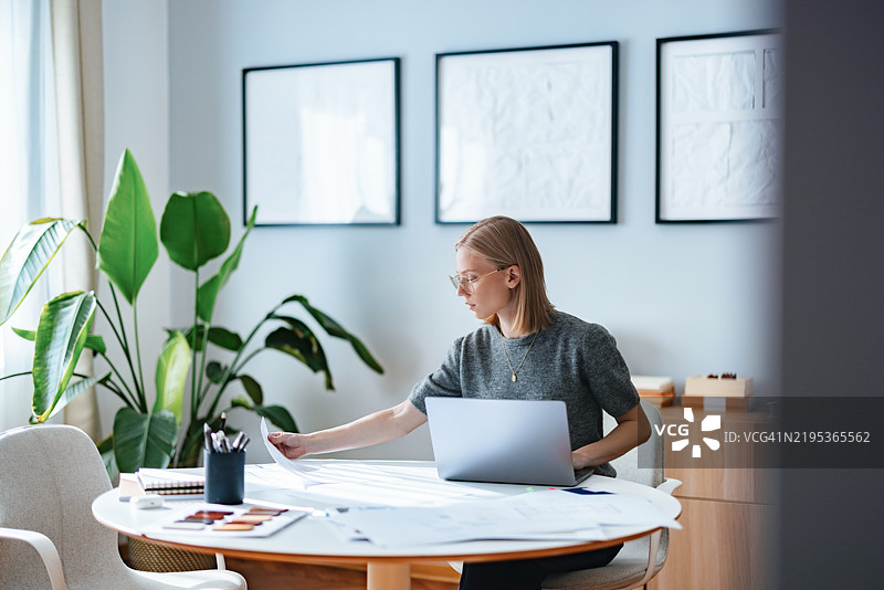 年轻女商人在现代家居办公室中与绿色植物一起工作图片素材