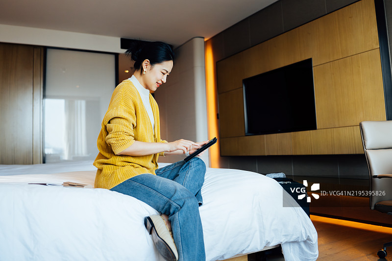 亚洲女商人在酒店房间的床上使用数字平板电脑。灵活的远程工作。与科技一起在户外工作。商业生活方式。工作与生活平衡及健康理念。图片素材