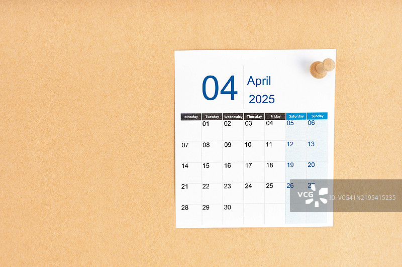 2025年4月的日历，木制图钉放置在棕色背景上，留有空白区域。图片素材