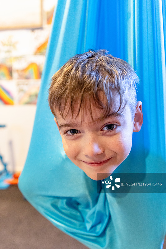 年轻男孩在丝绸感官秋千中进行自我调节图片素材