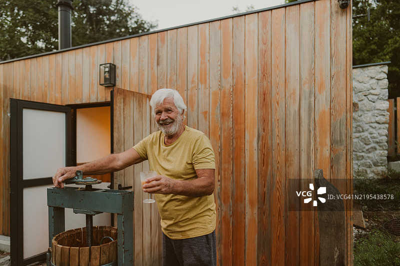 老年男子在户外用木制葡萄压榨机压榨葡萄图片素材