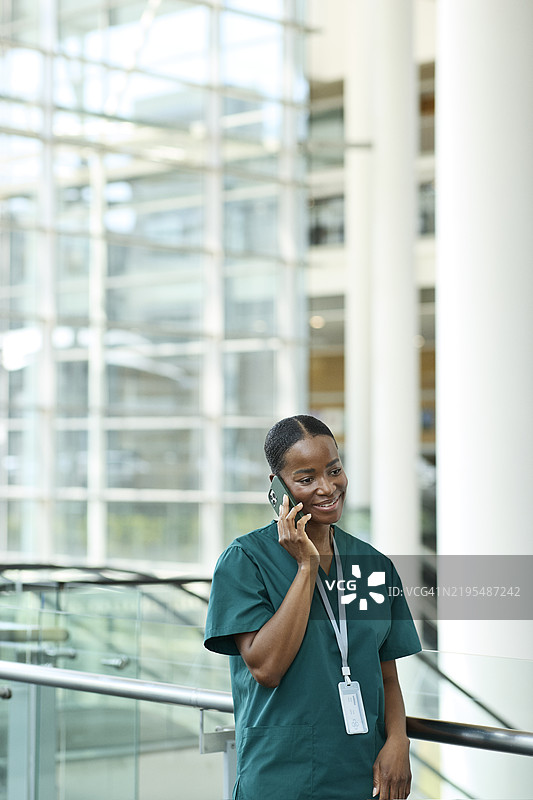 微笑的护士在栏杆旁通过智能手机交谈图片素材