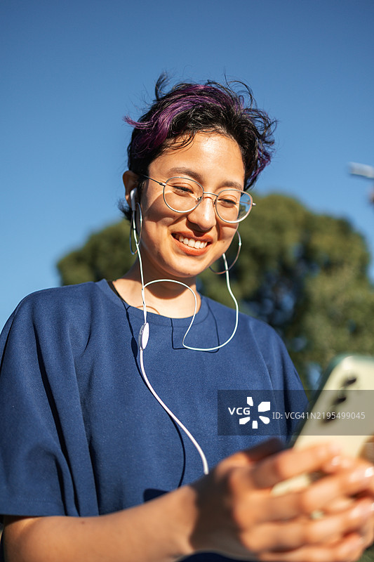 年轻女性在明亮的天空下享受户外无线通话图片素材