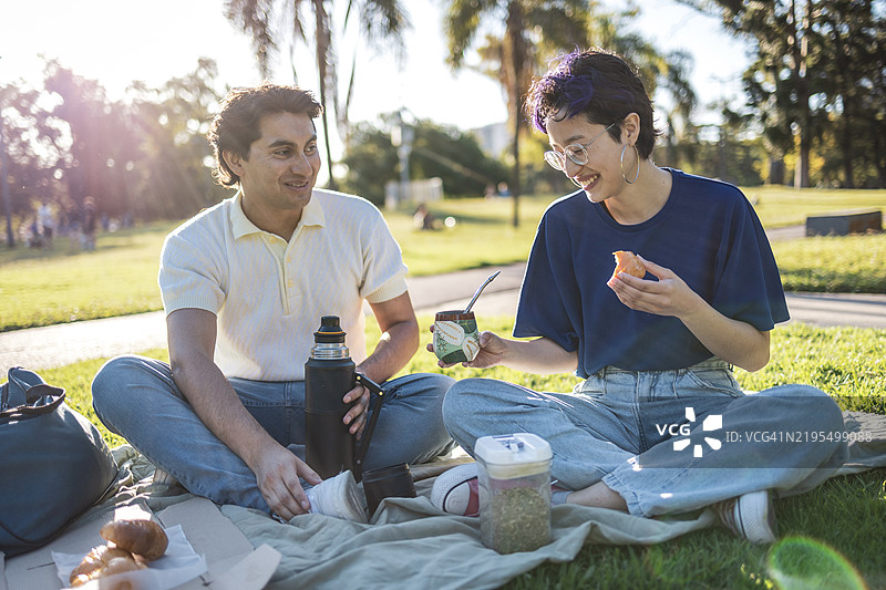 朋友们在公园野餐时享受马黛茶和糕点图片素材