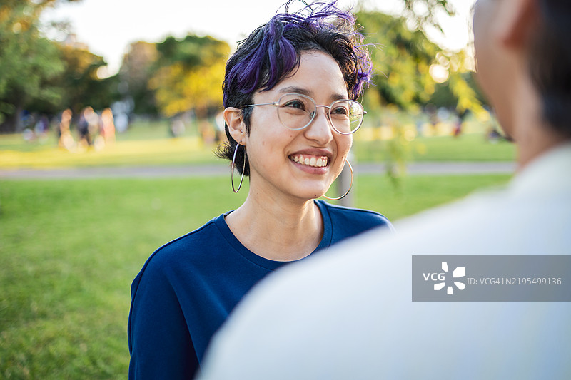 两个年轻朋友在美丽的公园里微笑着享受时光图片素材
