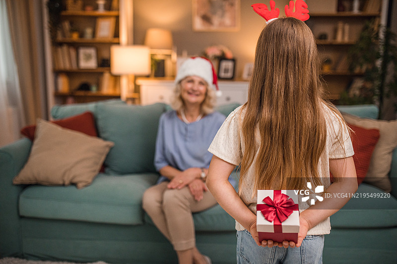 小女孩背对着镜头，将礼物递给微笑的奶奶图片素材