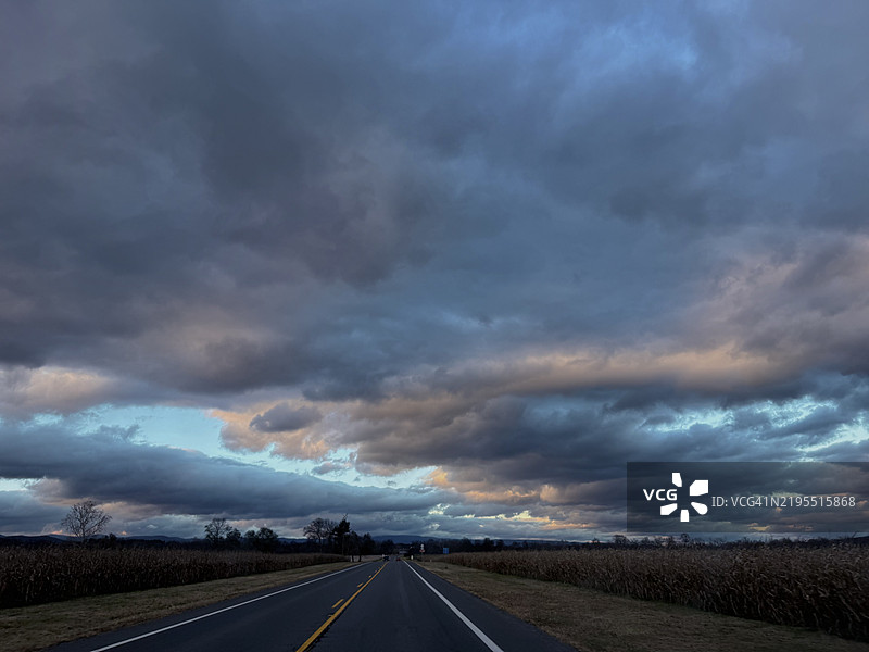 在云雾弥漫的天空下，穿越田野的空旷道路，位于美国弗吉尼亚州的谢南多厄县图片素材