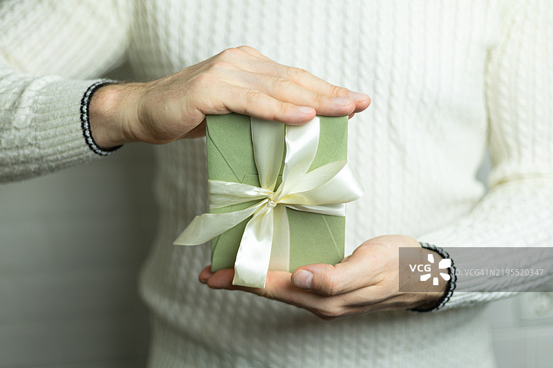 一个男人手里拿着一张带有白色缎带的礼品券图片素材