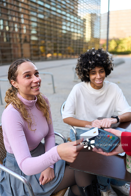 少女在户外咖啡馆用非接触式信用卡付款图片素材