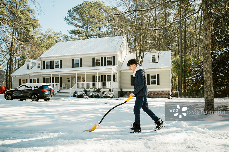 少年在车道上铲雪图片素材