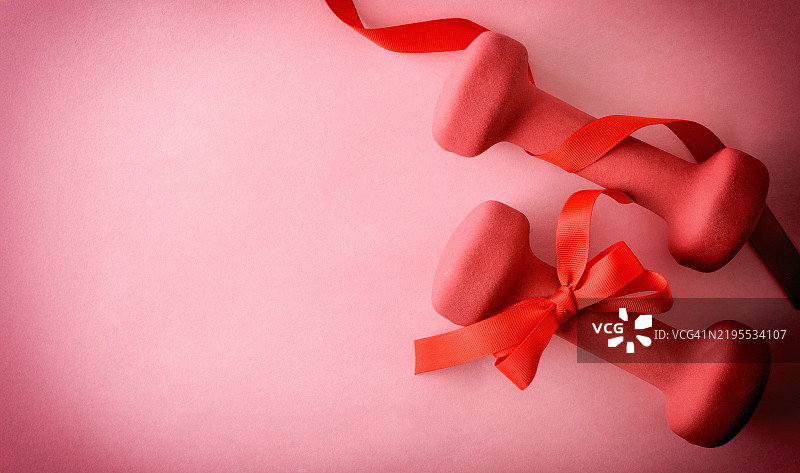 红色哑铃的健身礼物概念，背景为纯色隔离。图片素材